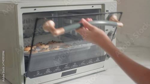 Cropped shot of girl setting oven temperature when baking cookies with chocolate chips photo
