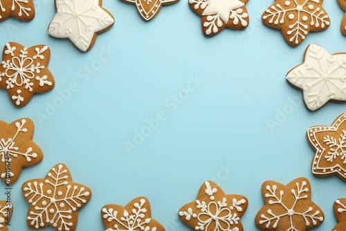 Frame made of tasty star shaped Christmas cookies with icing on light blue background, flat lay. Space for text