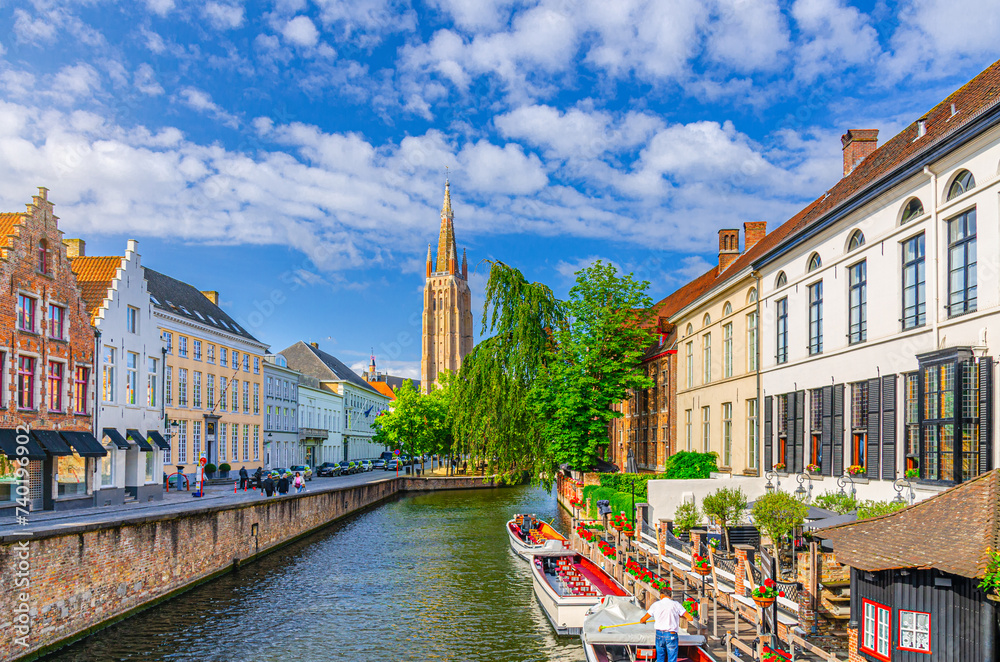 Bruges cityscape, Roman Catholic Church of Our Lady, Dijver water canal with promenade embankment, boat near wharf and medieval buildings, Brugge old town, Bruges city centre, Flemish Region, Belgium