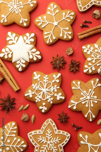 Tasty star shaped Christmas cookies with icing and spices on red background, flat lay