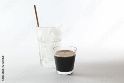 Coffee and ice cubes in different glasses on white background