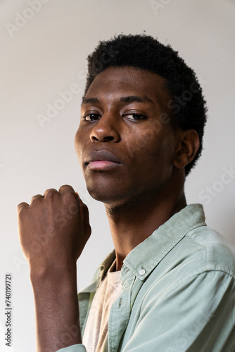 Side view portrait of young adult man looking to the camera while raising fist