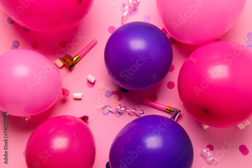 Balloons, confetti and party horns on pink background