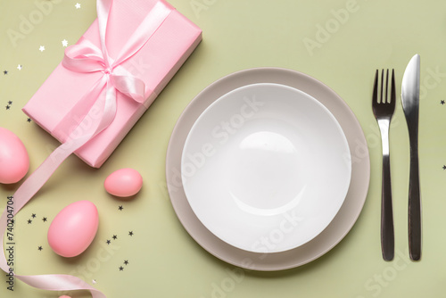 Beautiful Easter table setting with gifts and eggs on green background