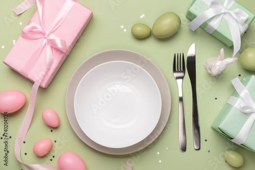 Beautiful Easter table setting with gifts and eggs on green background