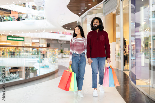 Positive Indian Couple Holding Colorful Shopper Bags, Walking By Mall