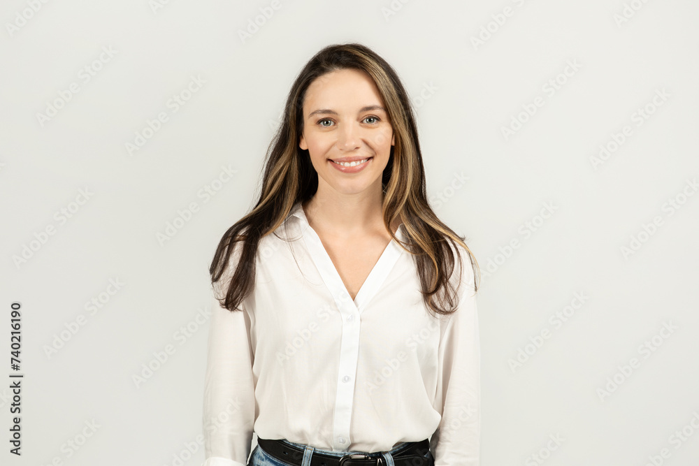 A friendly young woman with long brunette hair, wearing a crisp white blouse and blue jeans A friendly young woman with long brunette hair, wearing a crisp white blouse and blue jeans