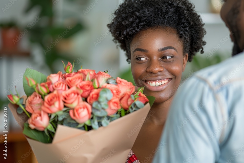 A joyful woman stands against a wall, beaming with a bouquet of beautifully arranged flowers, both real and artificial, showcasing her love for floristry and indoor plants
