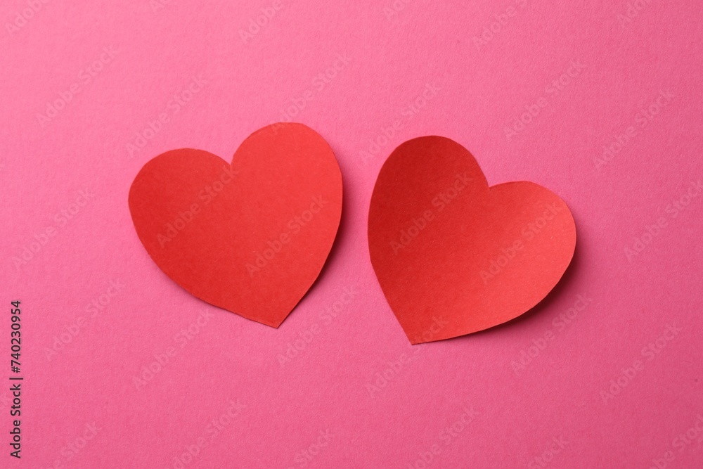 Red paper hearts on pink background, flat lay