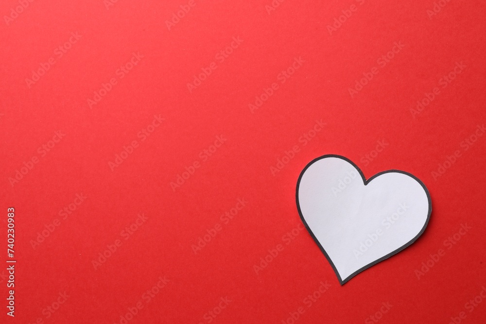White paper heart on red background, top view. Space for text