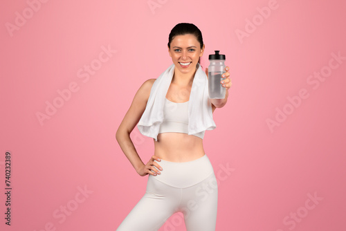 Radiant young woman in a white sports bra and leggings holding a water bottle