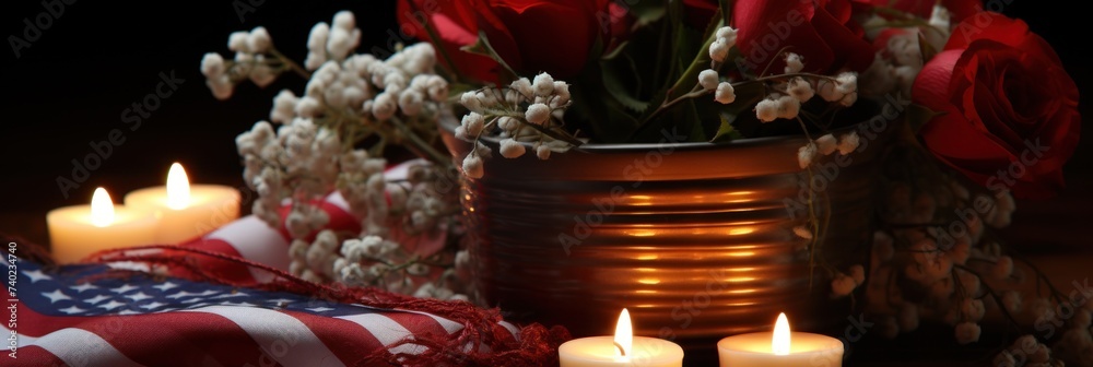 Vase filled with red roses stands next to two lit candles
