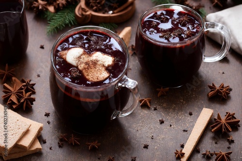 Mulled wine with chocolate and spices on a wooden background.
