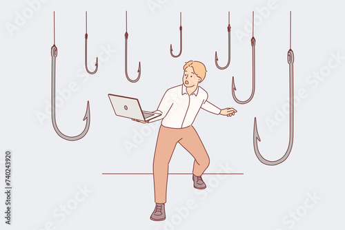 Trap hooks around man with laptop as metaphor for dangers of deception and scammers on internet