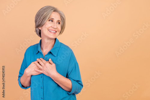 Portrait of appreciative pensioner person wear stylish shirt arms on chest look at sale empty space isolated on beige color background