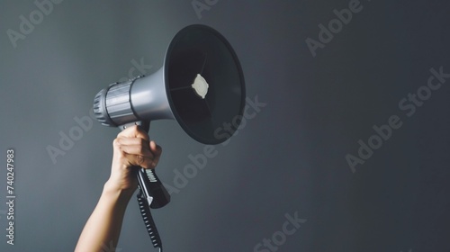 Female hand holding megaphone on grey background