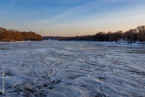 Ice floats on the water, frosty evening, cold, winter landscape with a wide river. © Sergei