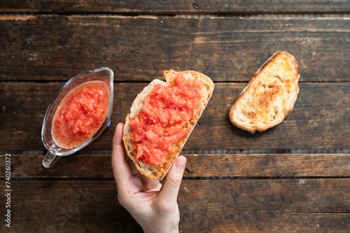 a hand holding freshly toasted bread with natural tomato and extra virgin olive oil in the morning before breakfast photo