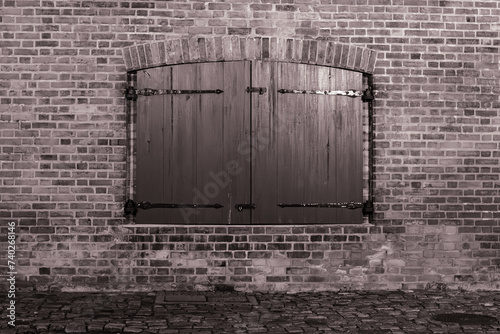 Zamknięta drewniana okiennica w ceglanej ścianie w czerni i bieli