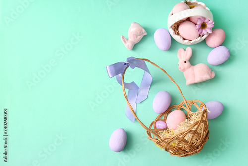 Baskets with painted Easter eggs, bunnies and flowers on turquoise background