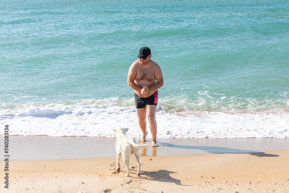 Friendship concept, man and dog playing together on the beach. Vacation and summer travel with pet. Friendship concept, man and dog playing together on the beach. Vacation and summer travel with pet.