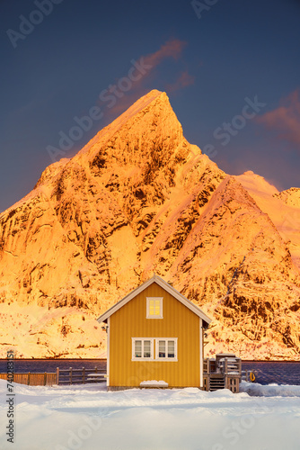 Lofoten islands beautiful nature sunset landscape in Norway and fishing town with scenic yellow rorbu house of Sakrisoy, Reine
