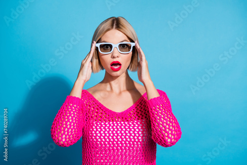 Photo portrait of attractive young woman amazed touch 3d glasses wear trendy pink knitted clothes isolated on blue color background