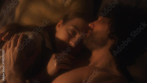 Young affectionate couple kissing and cuddling in bed during night at home photo
