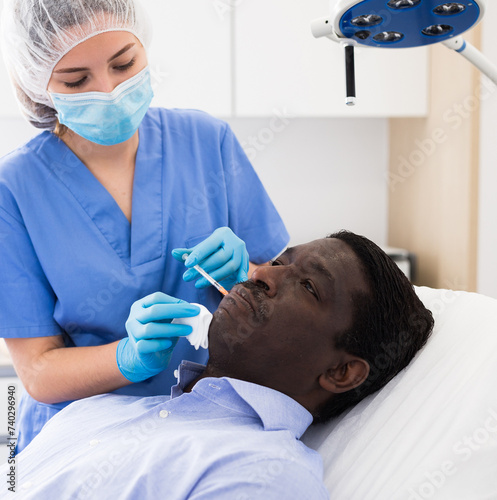 African american man getting injections for face skin tightening at aesthetic cosmetology clinic