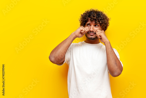 unhappy indian man crying and sad on yellow background, young offended guy in depression and stress upset photo