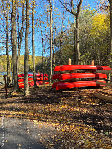 Red canoes on wooden supports. Forest in autumn. Nautical boat rental, river canoe, rabaska in a national park. Outdoor center for camping and fishing. photo