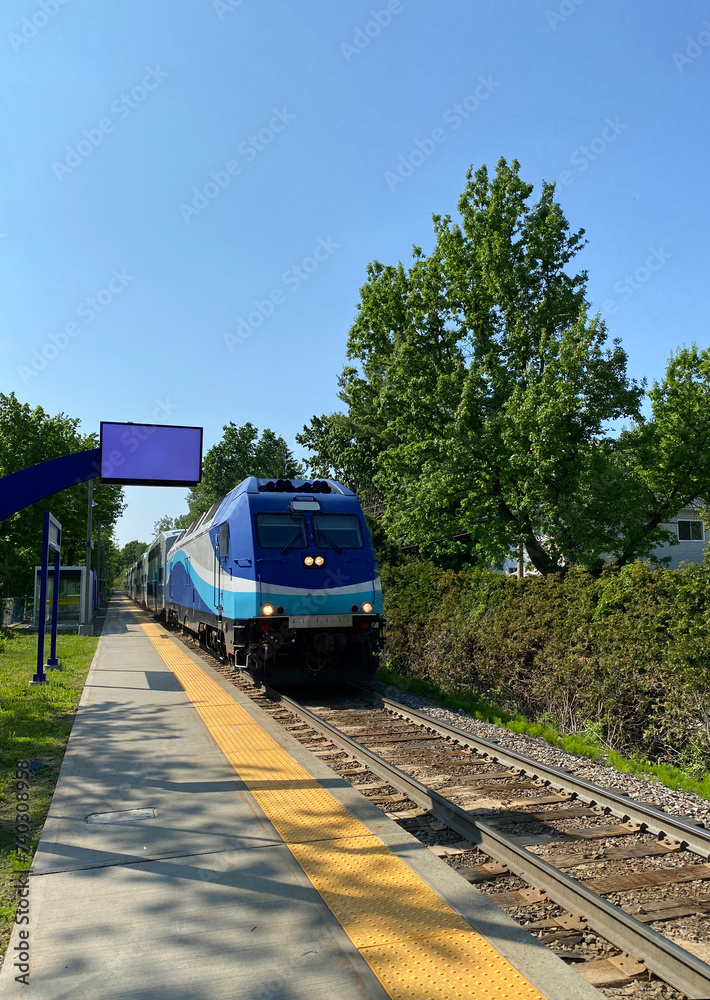 Naklejka premium Locomotive head of a train on the railway. City train at the station ready for departure. Suburban train arrival at the boarding platform. Display panel for travel times.