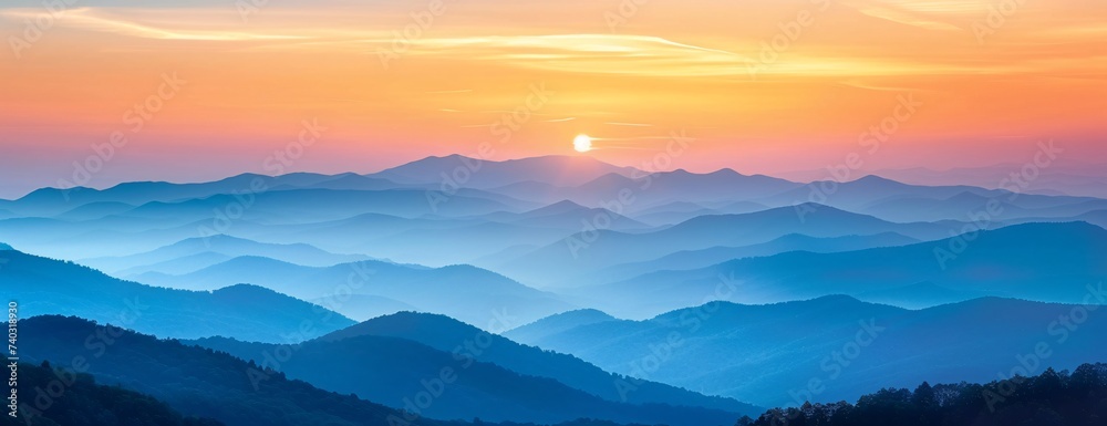 Panoramic view of layered mountains under sunset, gradient of blue to orange hues in sky