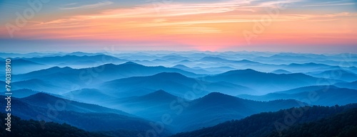 Hazy mountain ranges layered under soft pink and purple sunrise, fading into misty horizon