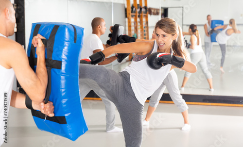 Sporty woman in boxing gloves training with trainer in gym