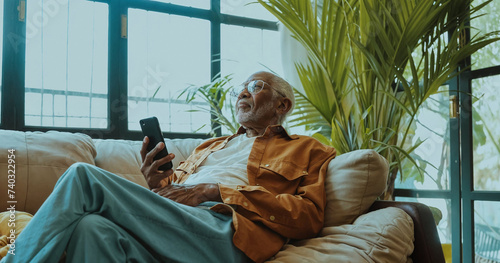 Hip fashionable old man, elderly hipster, black, at home on his phone, relaxed interior photo, short focus, details, vibrant and natural lighting