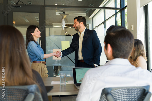 Businesspeople shaking hands in the middel of a meeting room