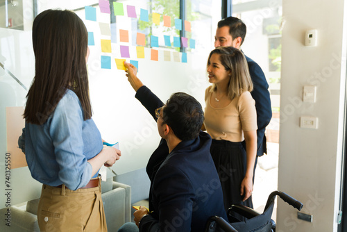 Team of businesspeople using sticky notes on a glass wall in a meeting room