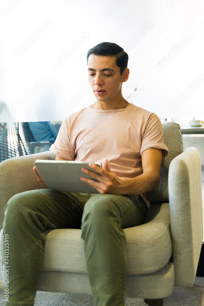 Businessman in casual clothing using a tablet computer for work while sitting in a comfy chair Businessman in casual clothing using a tablet computer for work while sitting in a comfy chair