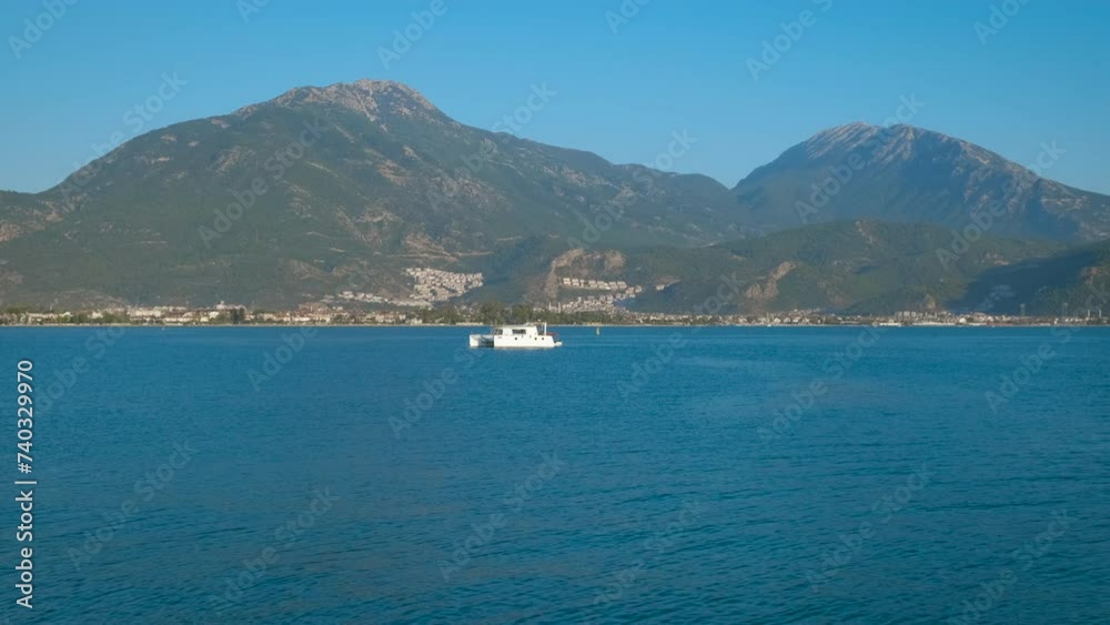 One sailing luxury catamaran against island. A view of sailing white yacht in the turquoise sea against mountains coast in the sun light. One sailing luxury catamaran against island. A view of sailing white yacht in the turquoise sea against mountains coast in the sun light.
