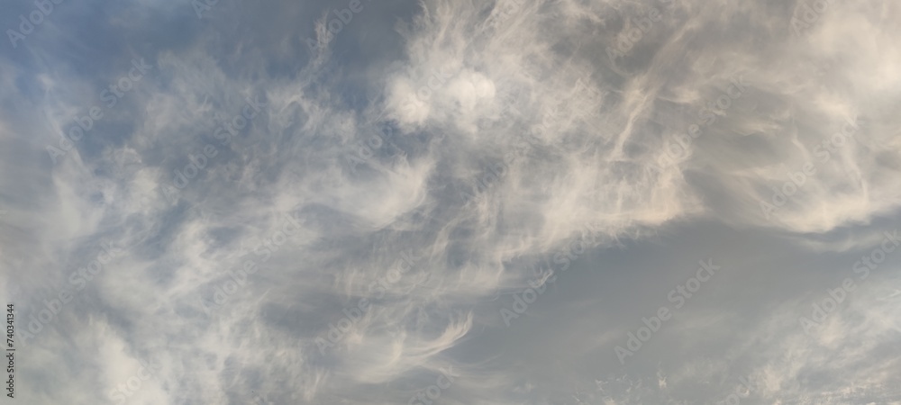 High cirrus clouds. Bright summer sky. High, semi-transparent cirrus clouds spread across the sky. Clouds of gray and white. They fill almost the entire space and the blue sky is visible through them.