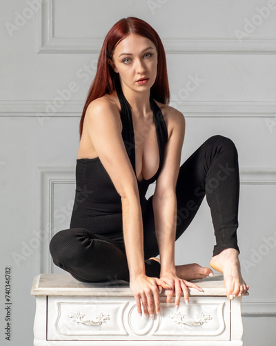 Woman on small dresser barefoot in black