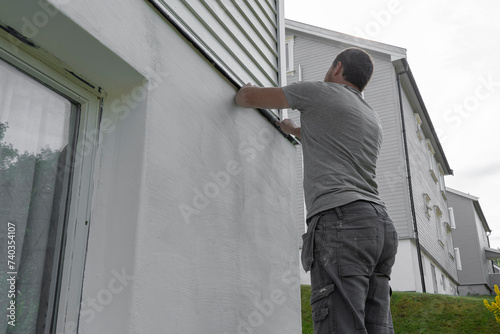 Preparing Perfection: Man Applies Masking Tape, Ready to Paint Wall.