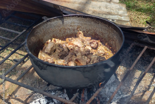 Meat stew in a cauldron on the fire. Preparation of meat for barbecue.