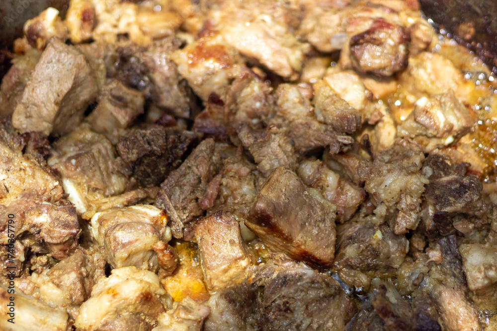 Close up of meat being cooked in a cauldron. Selective focus.