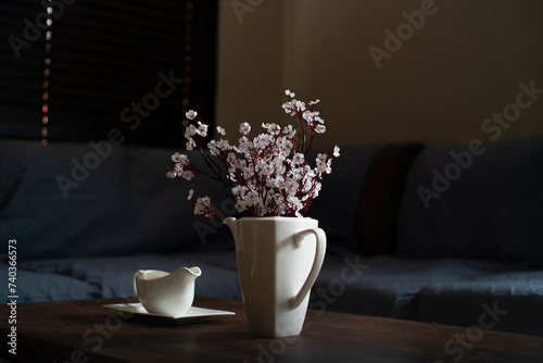 Decorado de interiores (sala), con salsera blanca, y una tetera blanca con ramo de flores blancas artificiales. photo