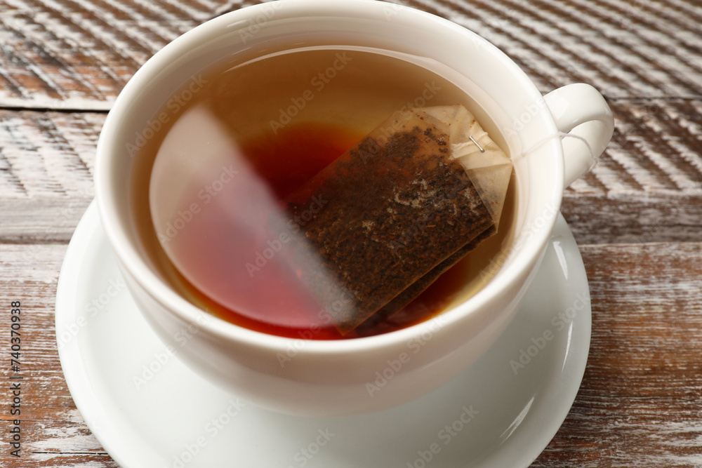 Tea bag in cup with hot drink on wooden rustic table, closeup Tea bag in cup with hot drink on wooden rustic table, closeup