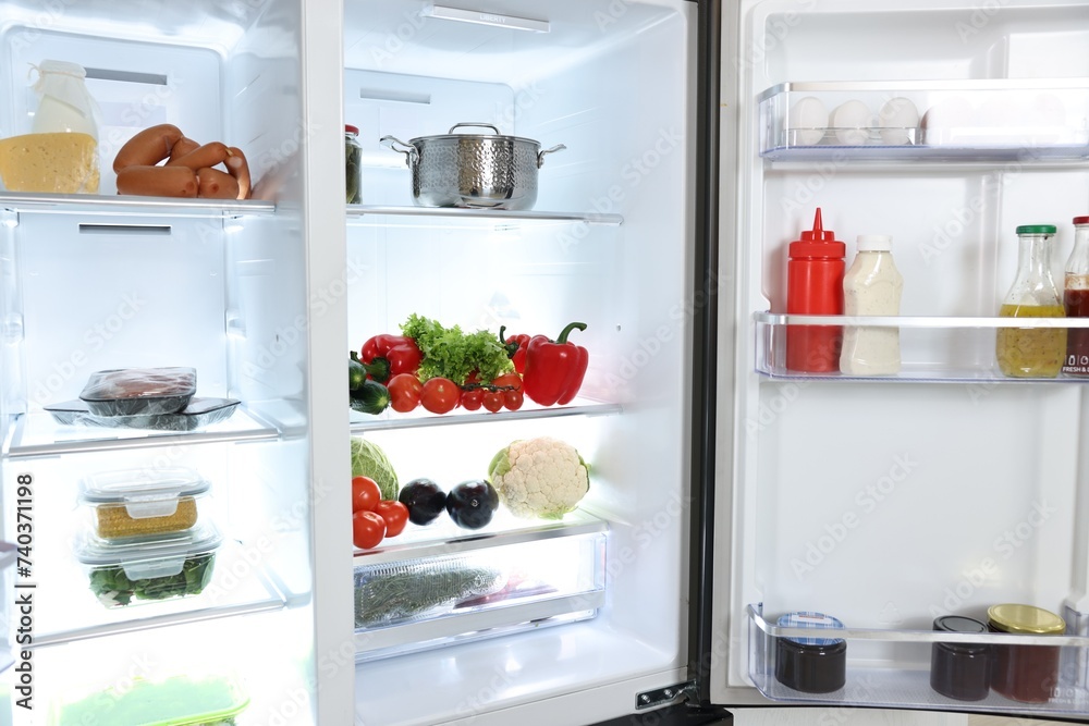 Modern open refrigerator full of different products Modern open refrigerator full of different products