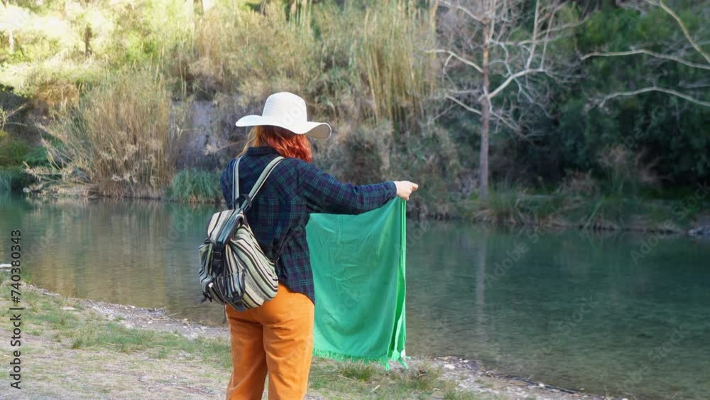 Woman by the river folding a green blanket Woman by the river folding a green blanket