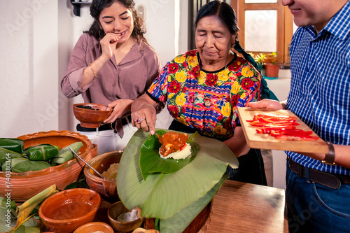 Beautiful Latin girl in the company of her grandmother and her boyfriend, make corn tamales for the party.